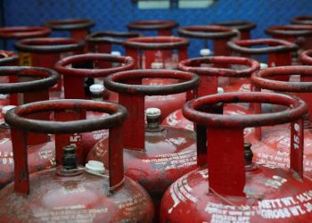 LPG cylinders ready for distribution with fuel pumps in the background, representing normal LPG, petrol, and diesel supply across India after backlog reduction.