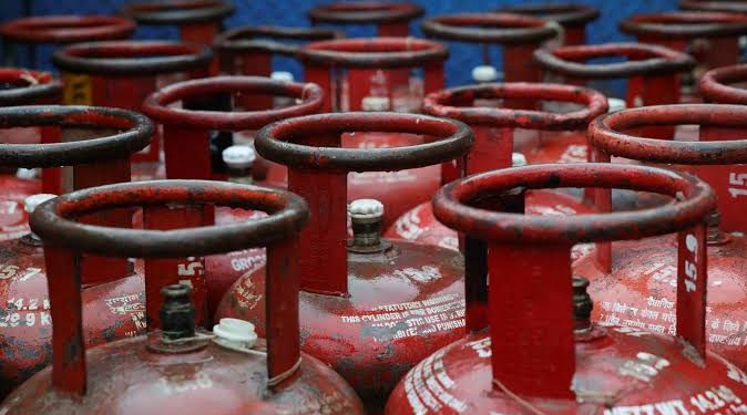 LPG cylinders ready for distribution with fuel pumps in the background, representing normal LPG, petrol, and diesel supply across India after backlog reduction.